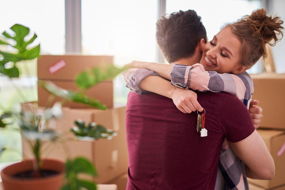 Couple enlacé, heureux qui emmenage dans son premier logement avec les clés en main
