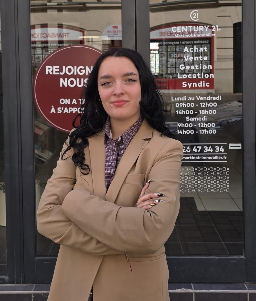 Camille, gestionnaire de copro, vêtue de la veste or devant l'agence Century 21 Martinot Immobilier à REIMS