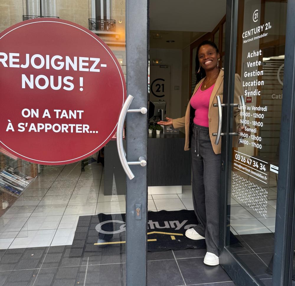 Nadège Hôtesse d'accueil chez Century 21 Martinot Immobilier ouvrant la porte de l'agence au 9 rue des Élus à REIMS